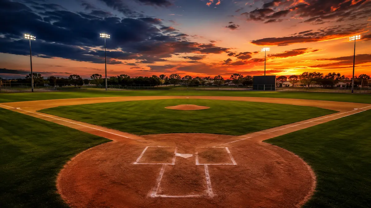 Empty amateur baseball diamond viewed from behind home plate at golden hour