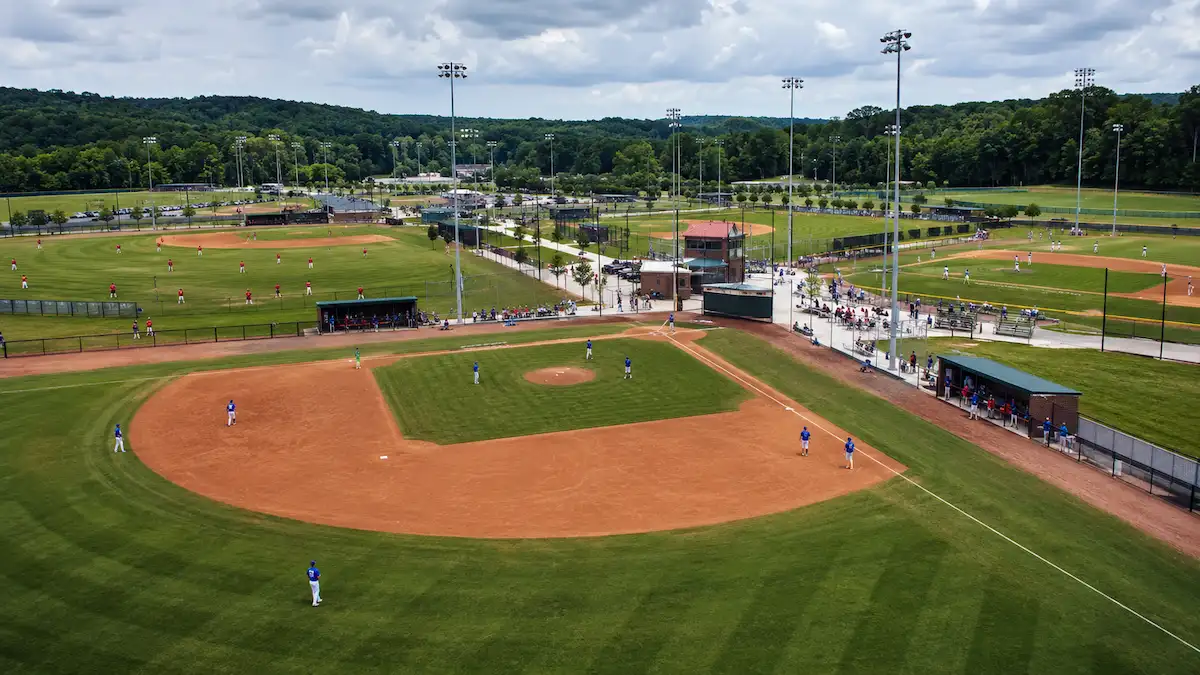 Multiple baseball teams warming up on adjacent fields at a multi-field sports complex